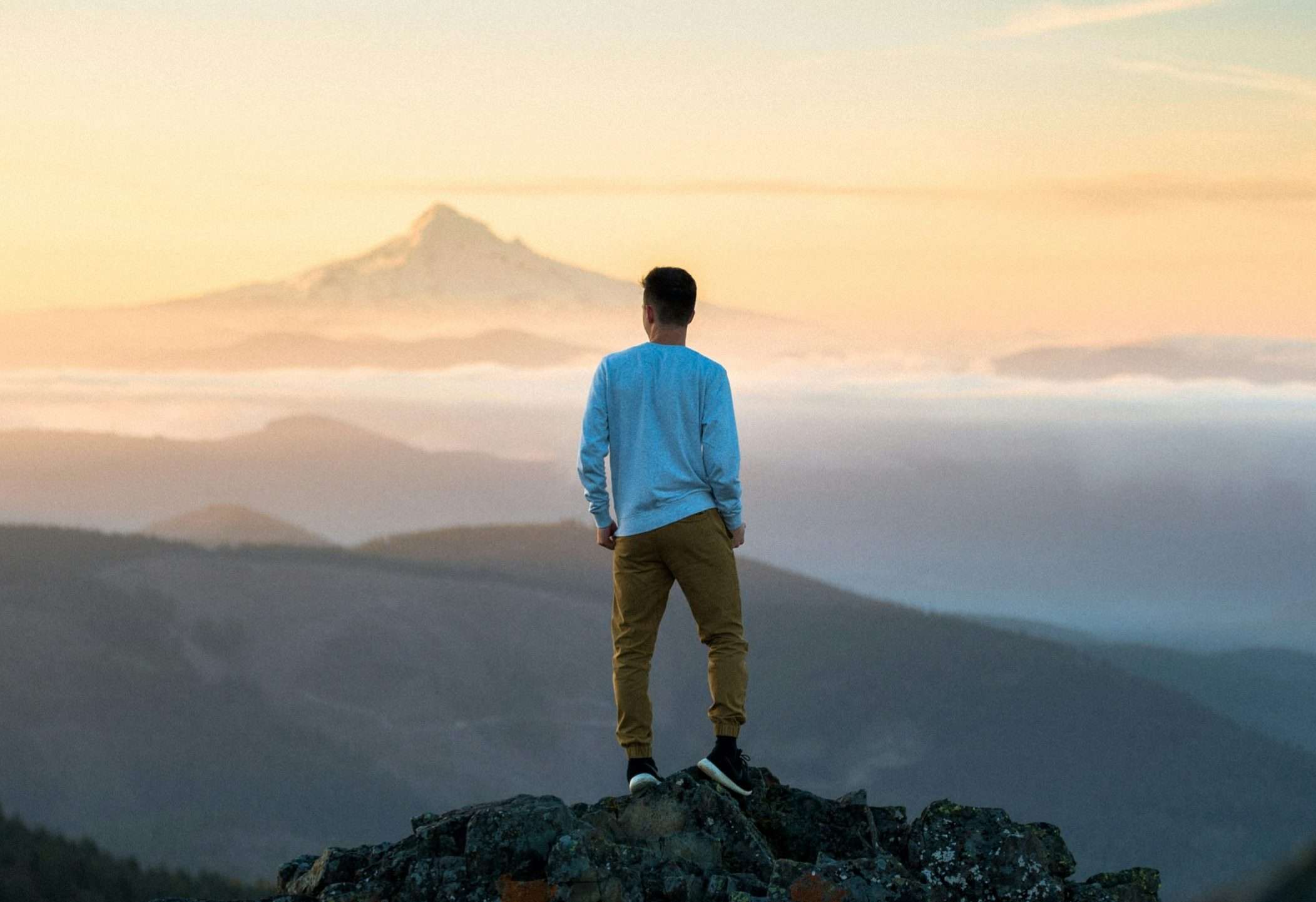 Man having thoughts while standing on top of a mountain.